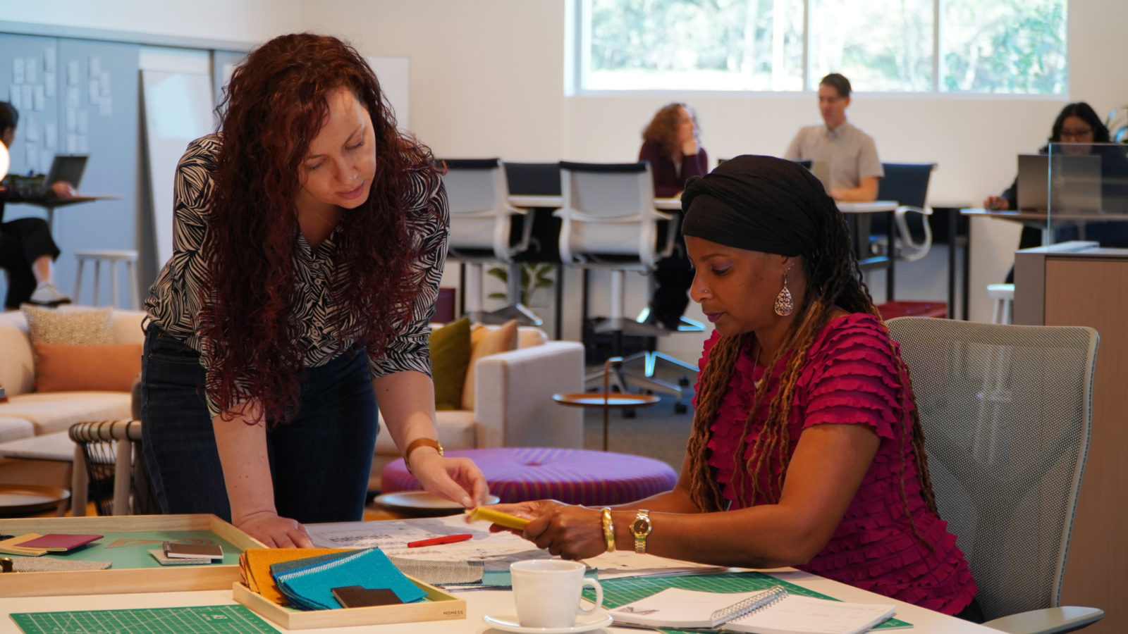 Two ladies at a table looking at materials and making design choices.
