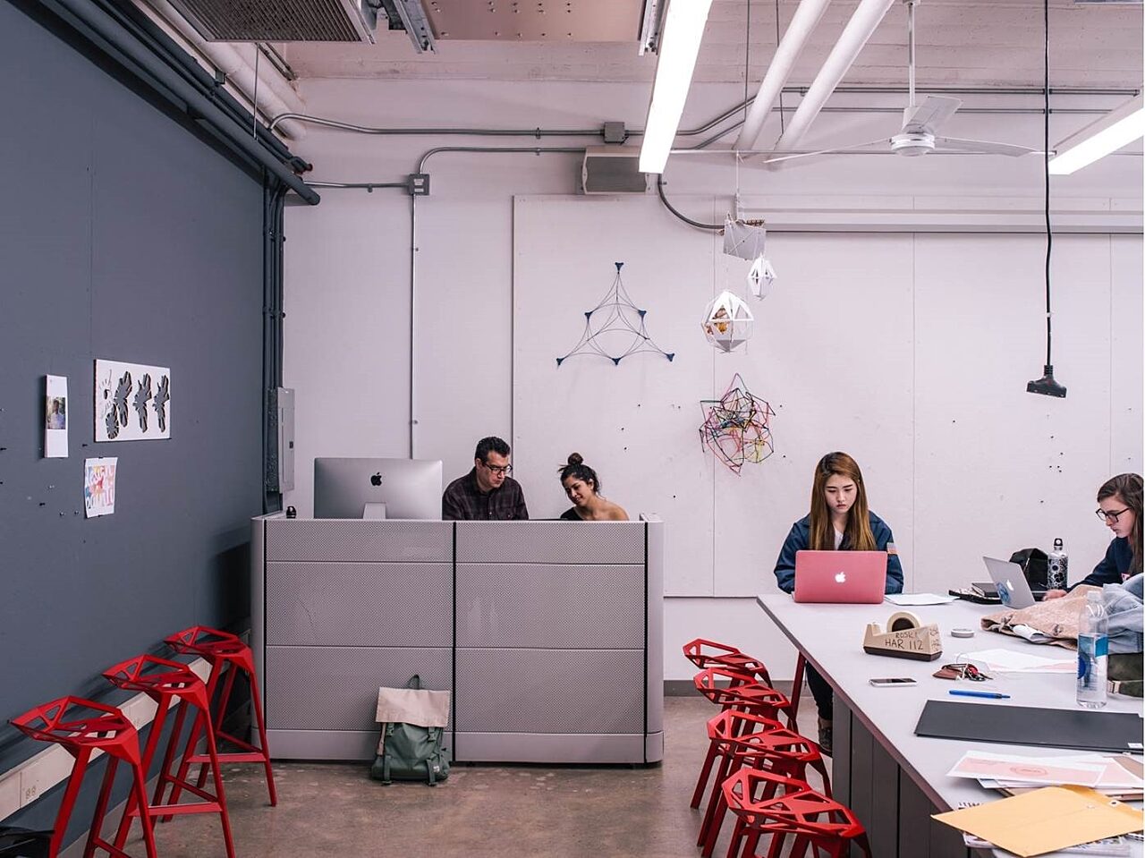 A lively collaborative brainstorming environment with a conference table surrounded by red stools encourages vigorous debates and ideation.