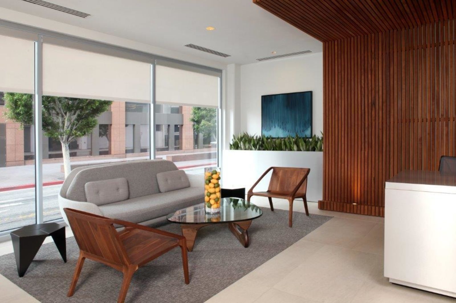 A lounge chair and coffee table are placed beside a white reception desk, creating a comfortable waiting area.