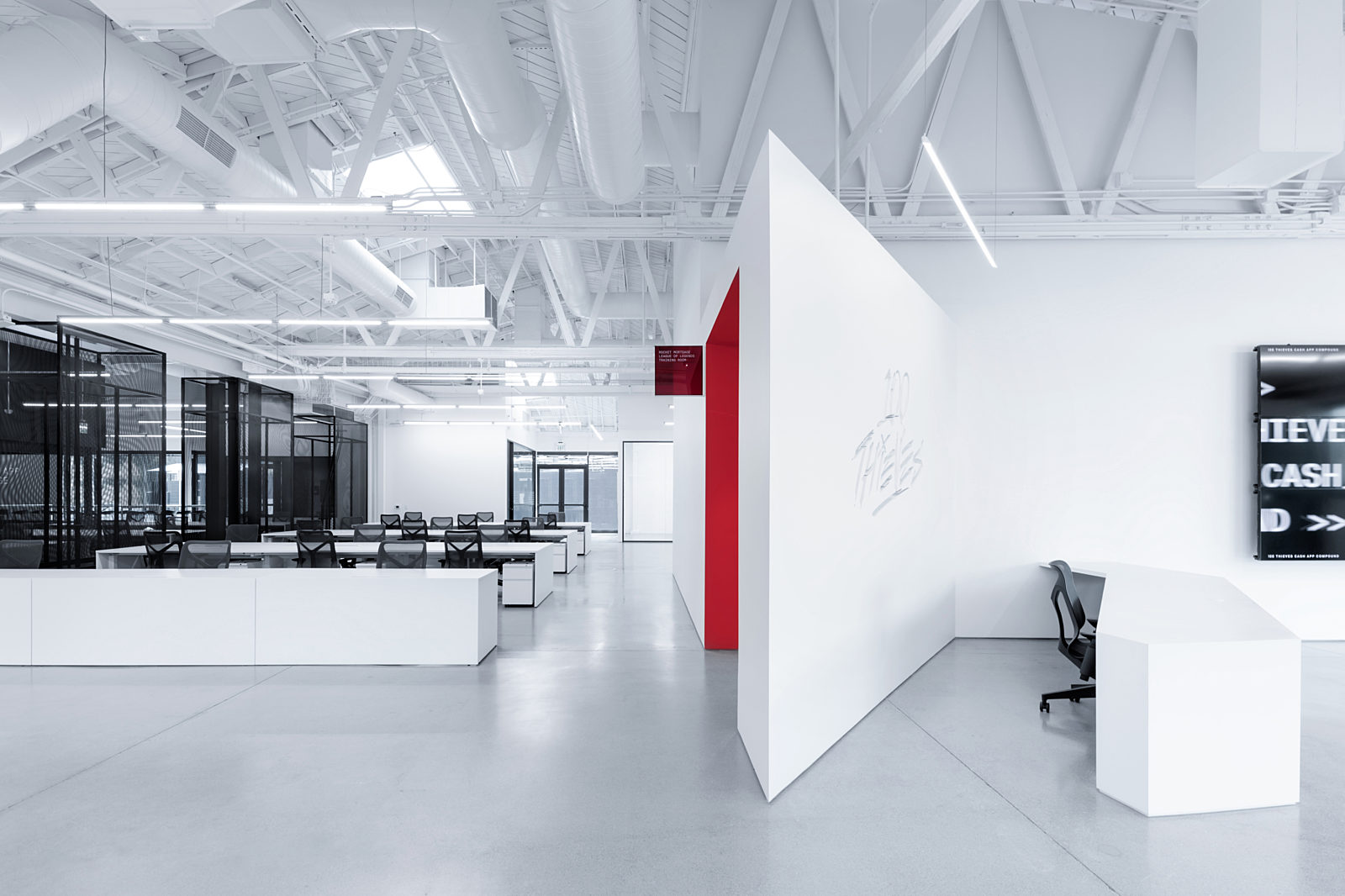 an open office that can contain multiple groups of people working together, and a white wall that divides the area  of working spaces and reception desk