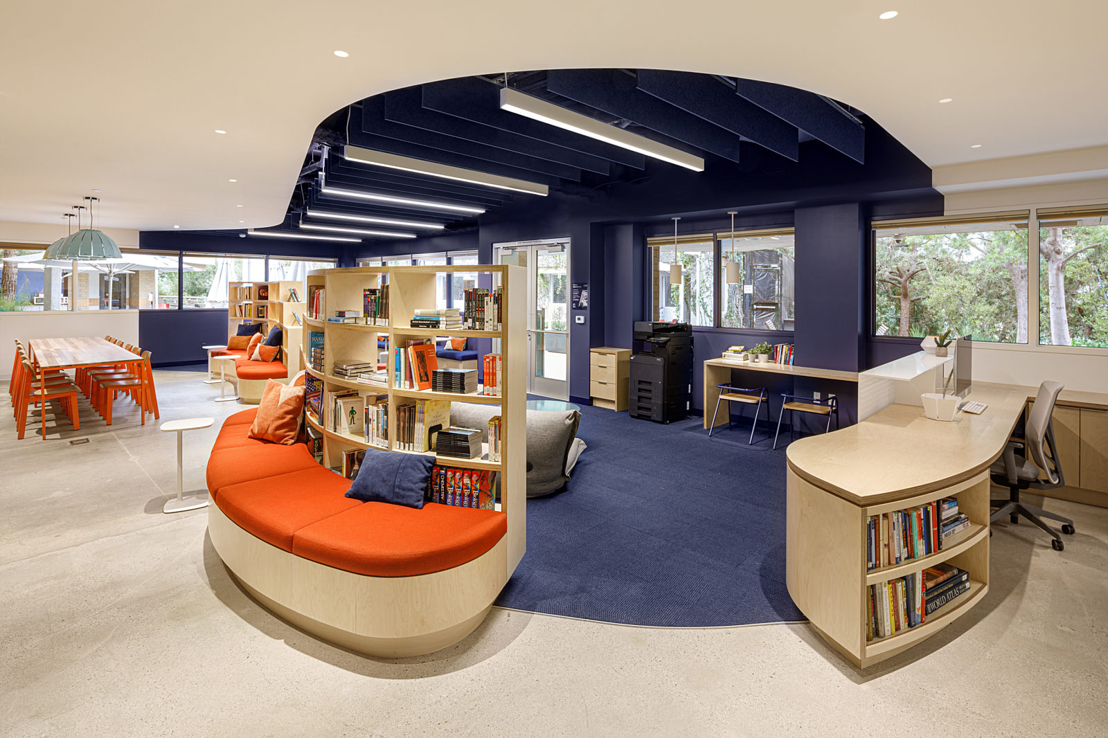 This tranquil public space is enhanced with a wooden curving desk, a bookshelf-style sofa, a white C-table, and a wooden drawer.
