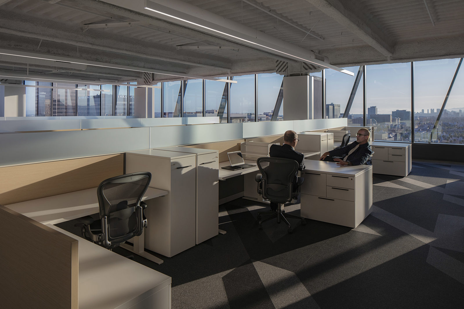 Wooden partitions create individual workstations in a space with stunning city views visible through the French windows.
