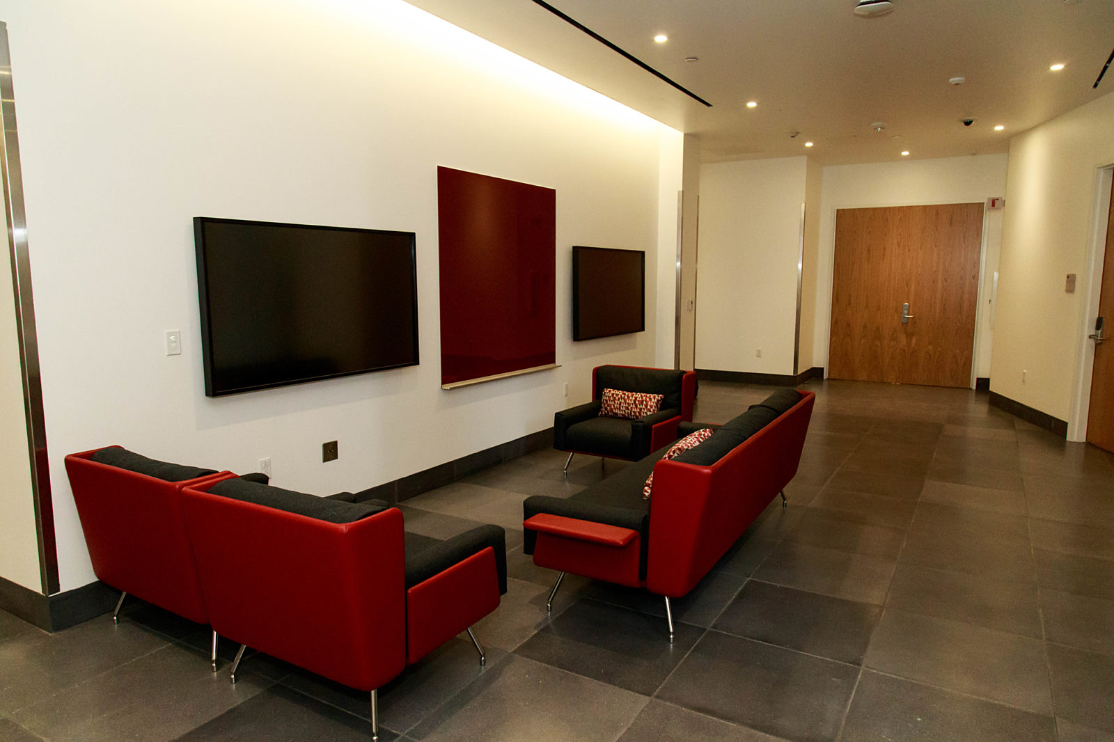 A lounge area with multiple lounge chairs and two televisions.