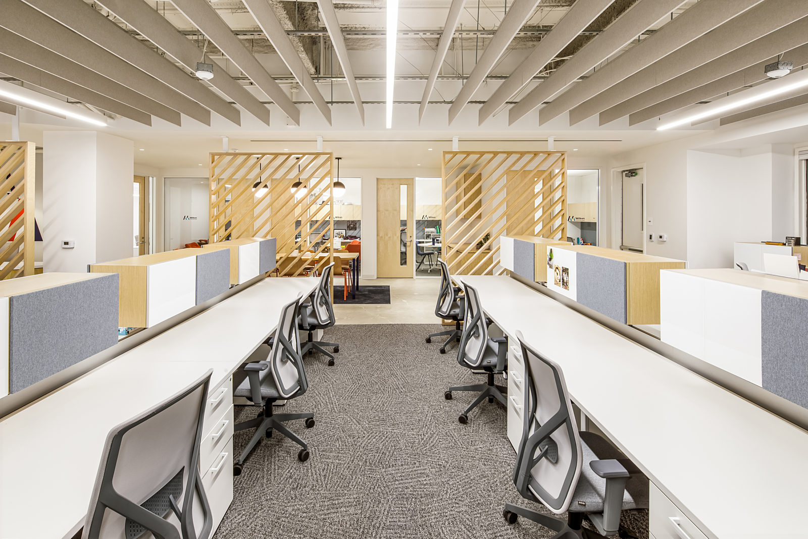 In front of the conference rooms, rows of workstations sit parallel to each other behind a wooden partition wall.