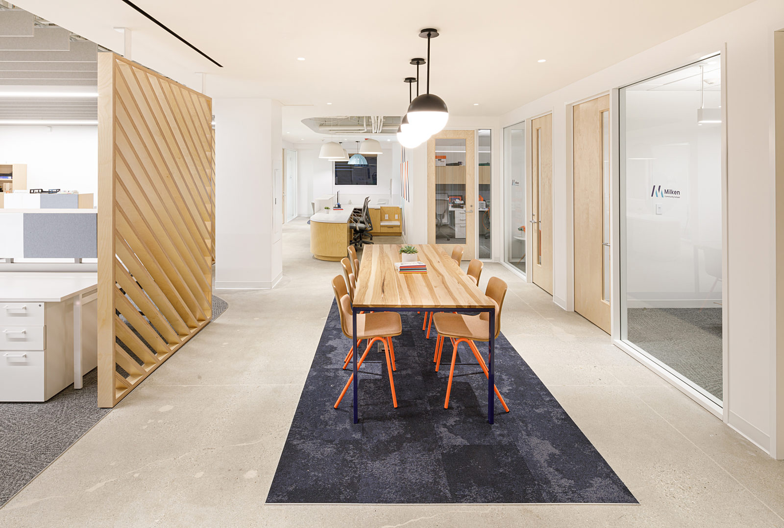 A hallway features a wooden partition, a sturdy wooden table, a wooden chair with orange iron legs, and a wooden counter desk.