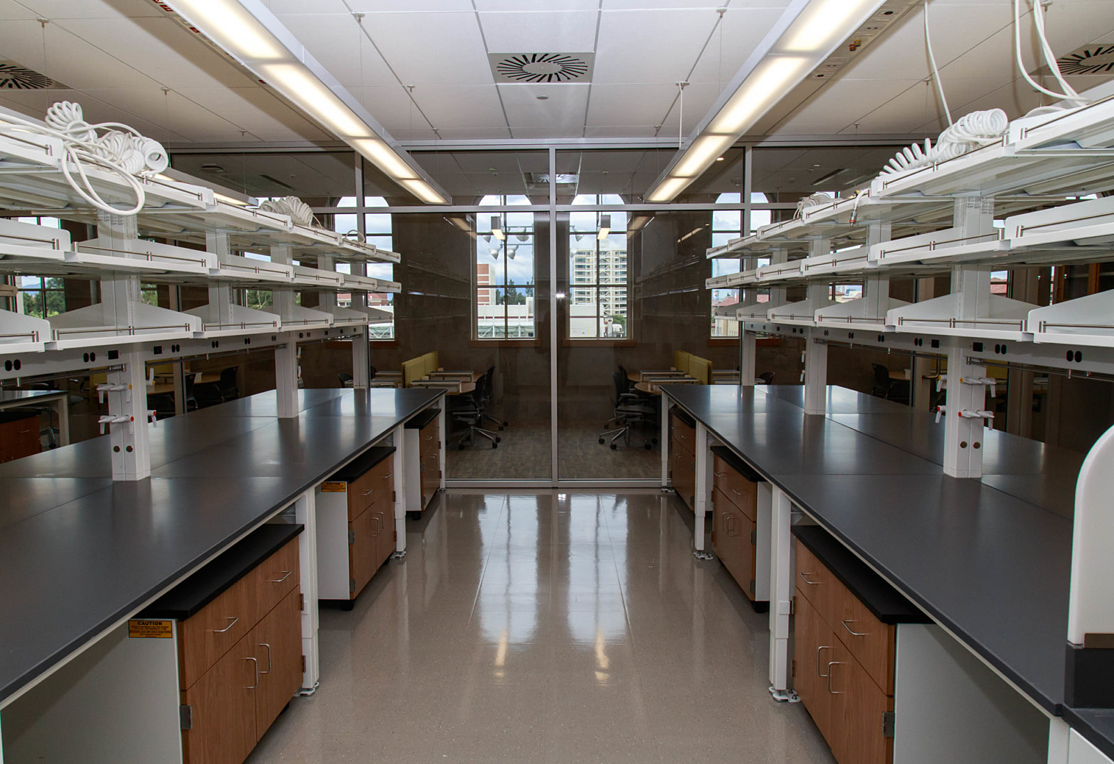 A laboratory with a black desk, a white shelf, and a French window serving as the background.