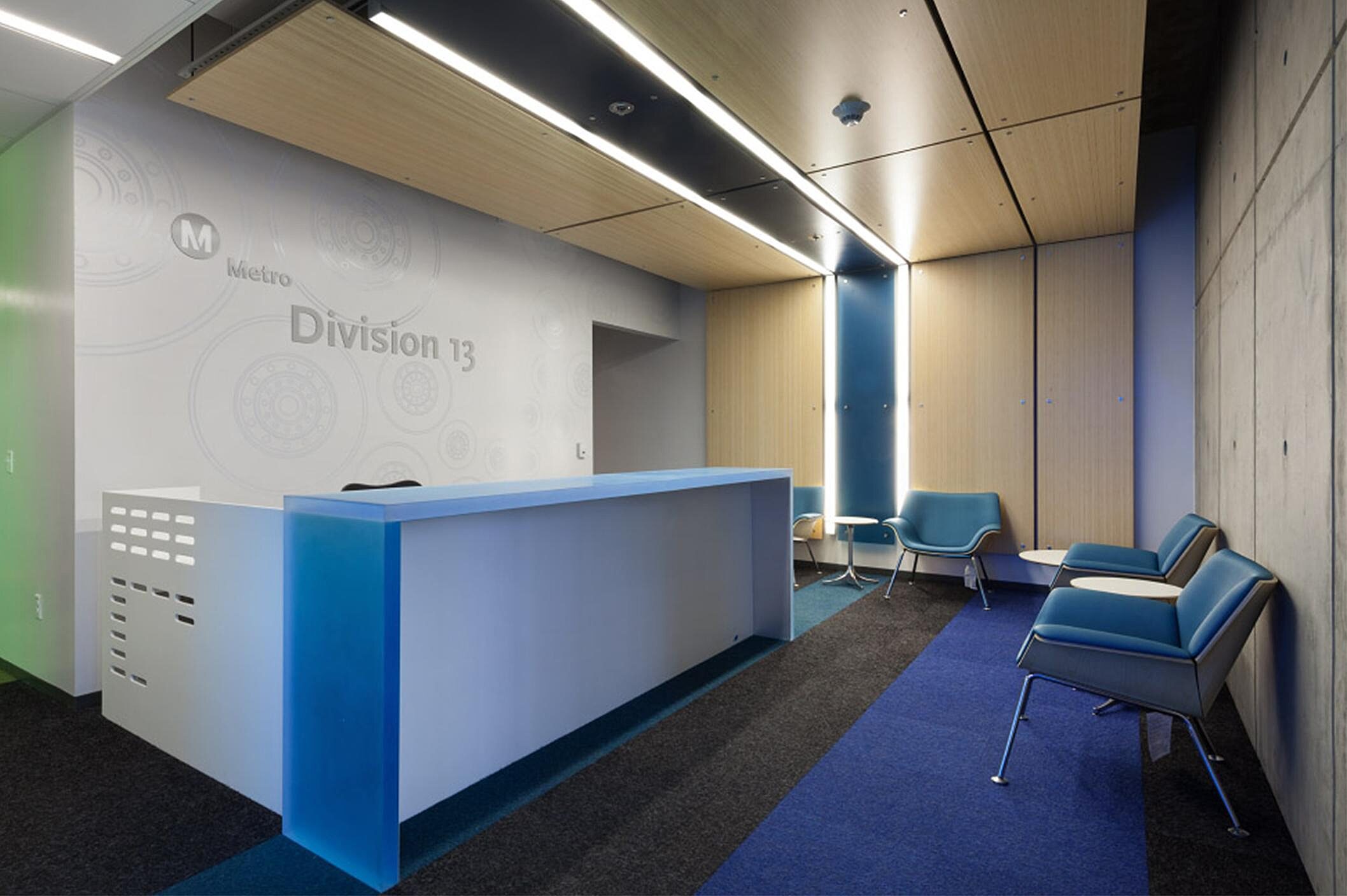 There are couple blue wing chair, white cafe table, and a blue and white front desk in the reception area