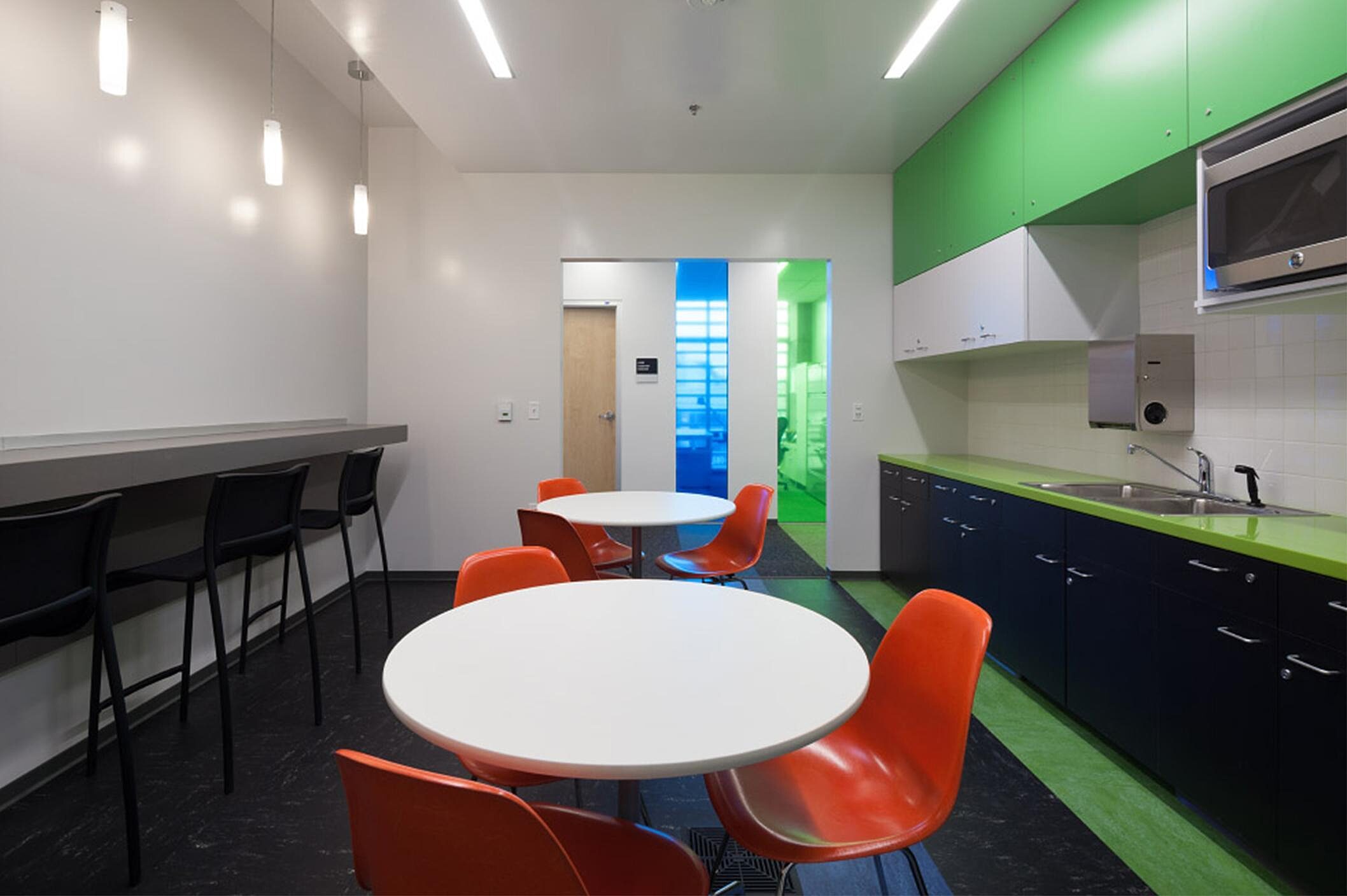 In a resting area, there are red cafe chairs, white cafe tables, and black steel stools.