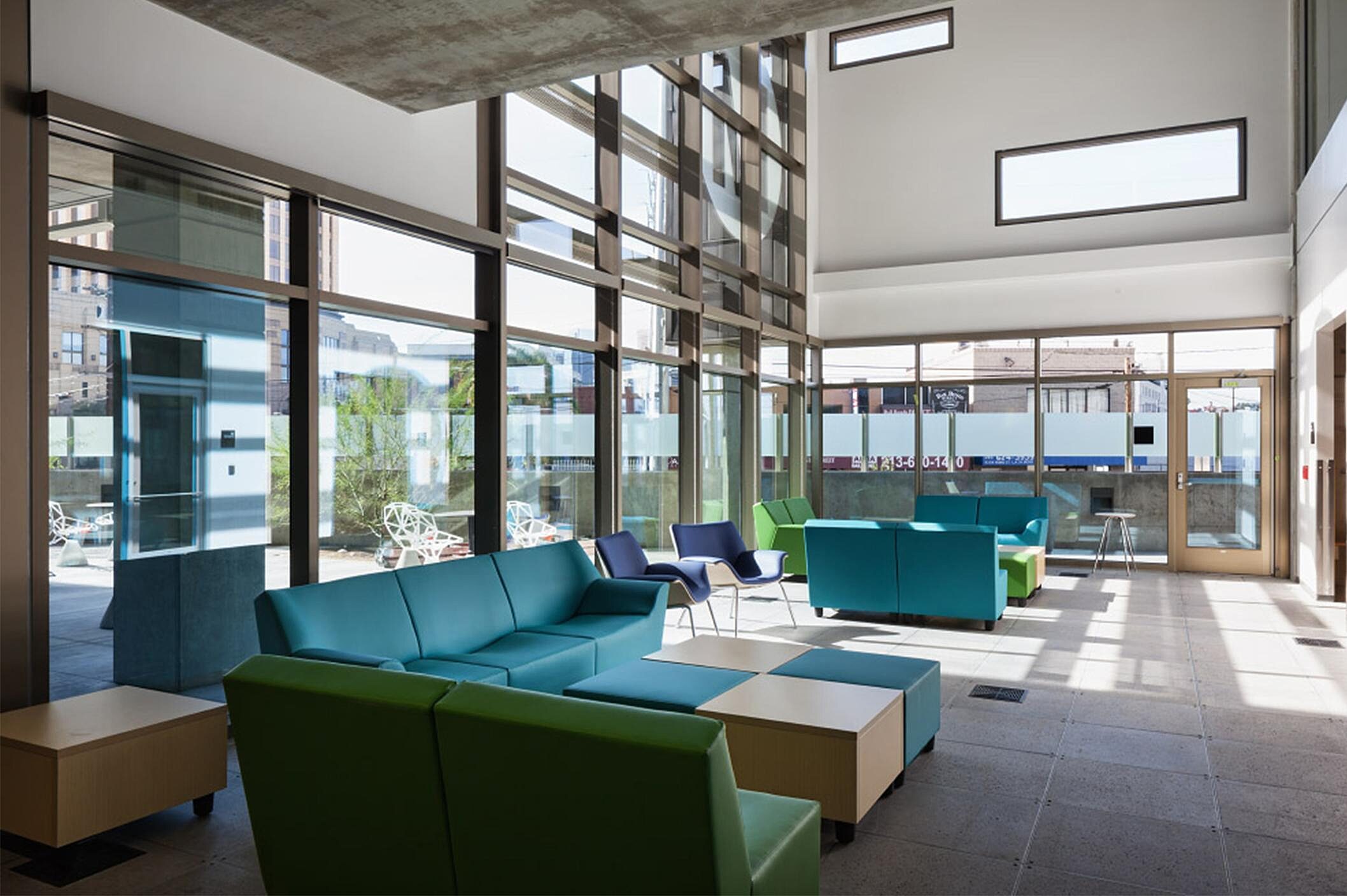 In a public area, there are blue and green sofa and a grid with blue and green coffee table.