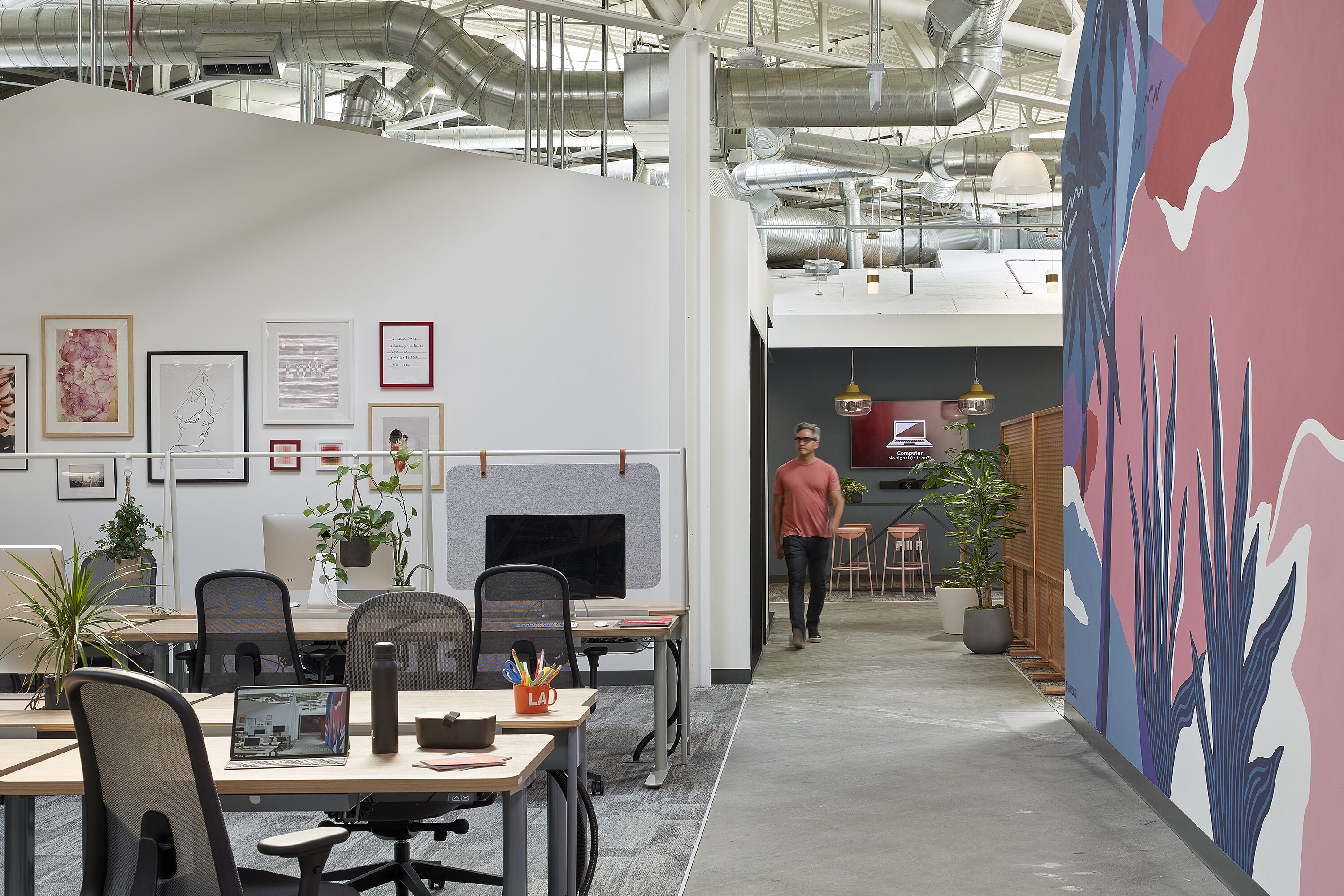 A spacious open office with numerous ergonomic chairs and wooden conference tables at the workstations.