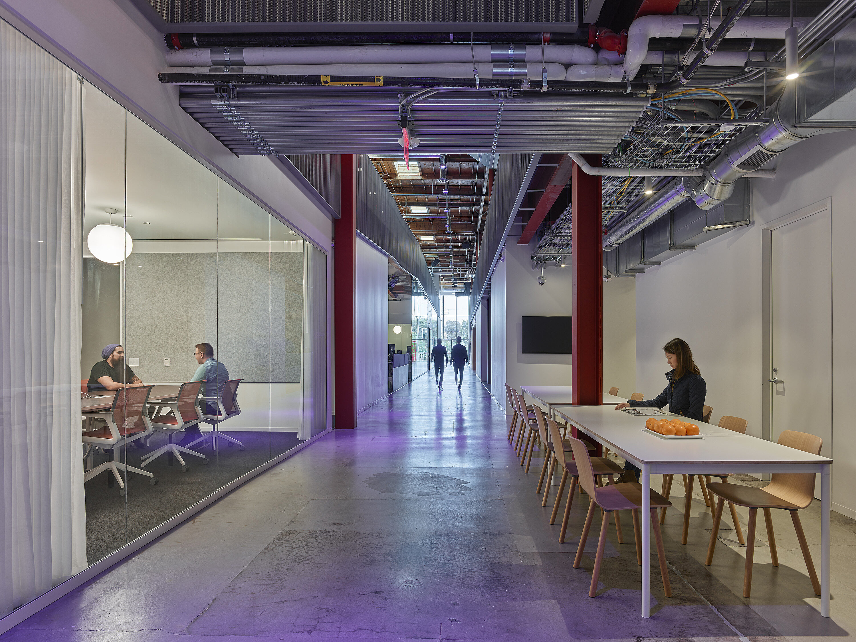 In a hallway outside of conference rooms, there's a white dining table and several wooden stools.