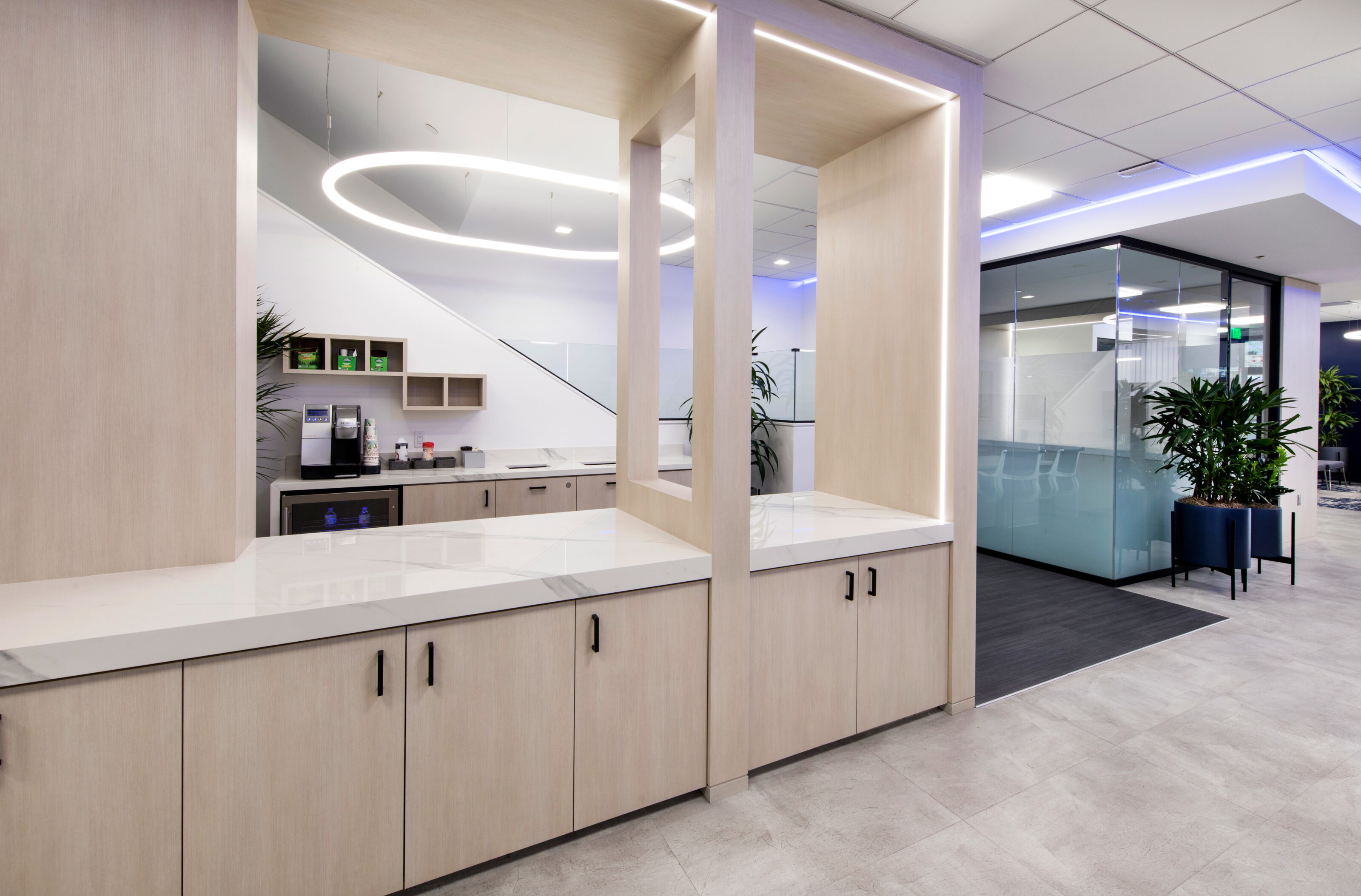 A contemporary break room with a light-colored bar table and storage adjacent to a private office.