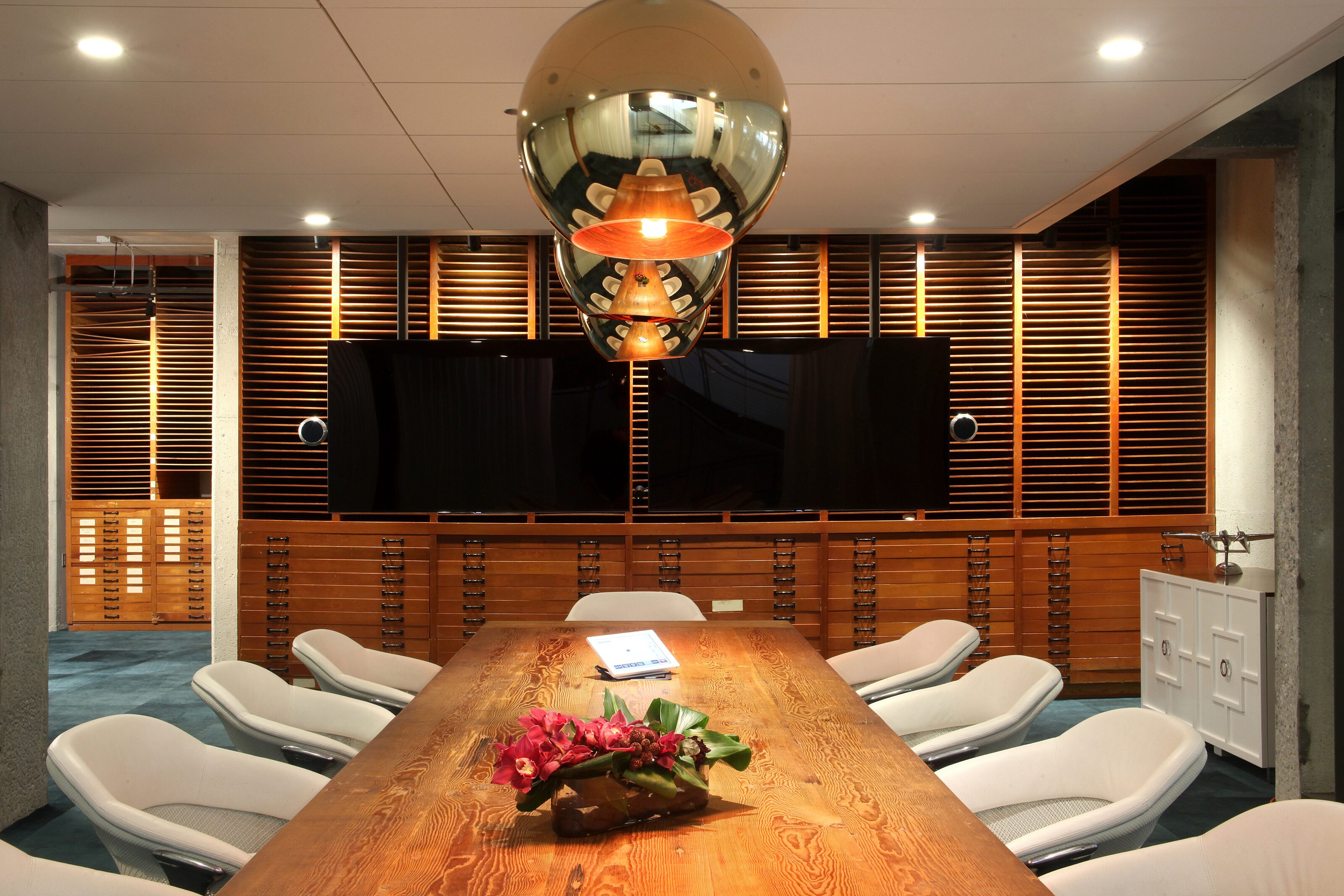Luxury wooden conference table surrounded by eight chairs in the room's center.