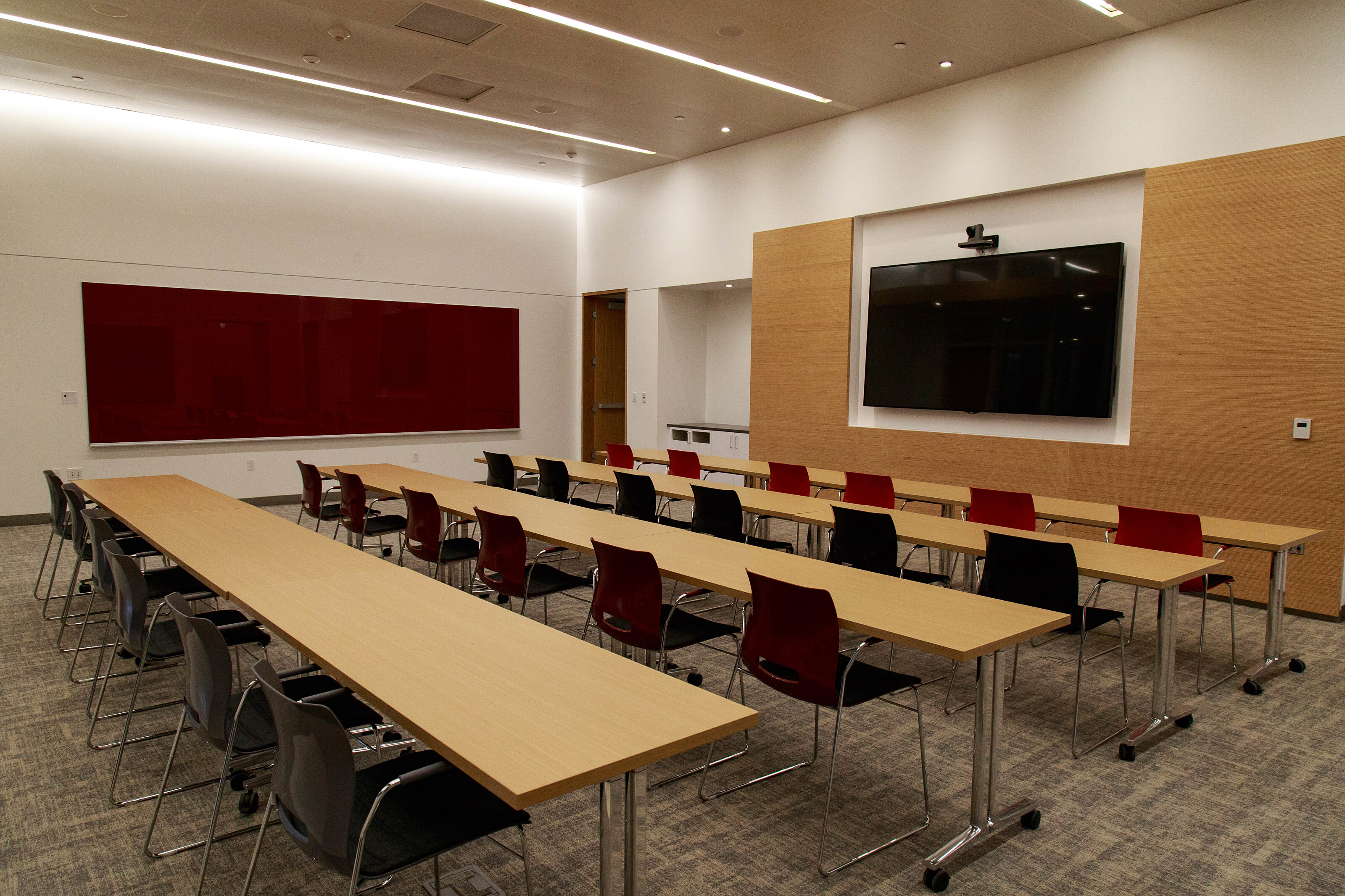 A well-lit, inviting room with wooden conference tables and foldable chairs, designed for productive meetings and stimulating discussions.