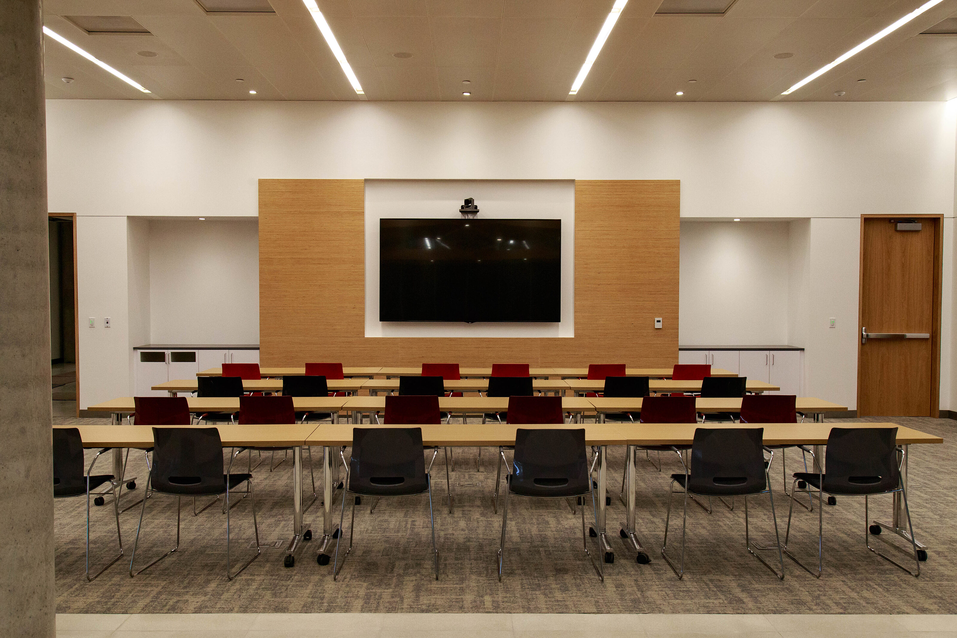 A bright and warm screen room featuring a row of wooden conference tables and folding chairs for productive meetings and discussions.
