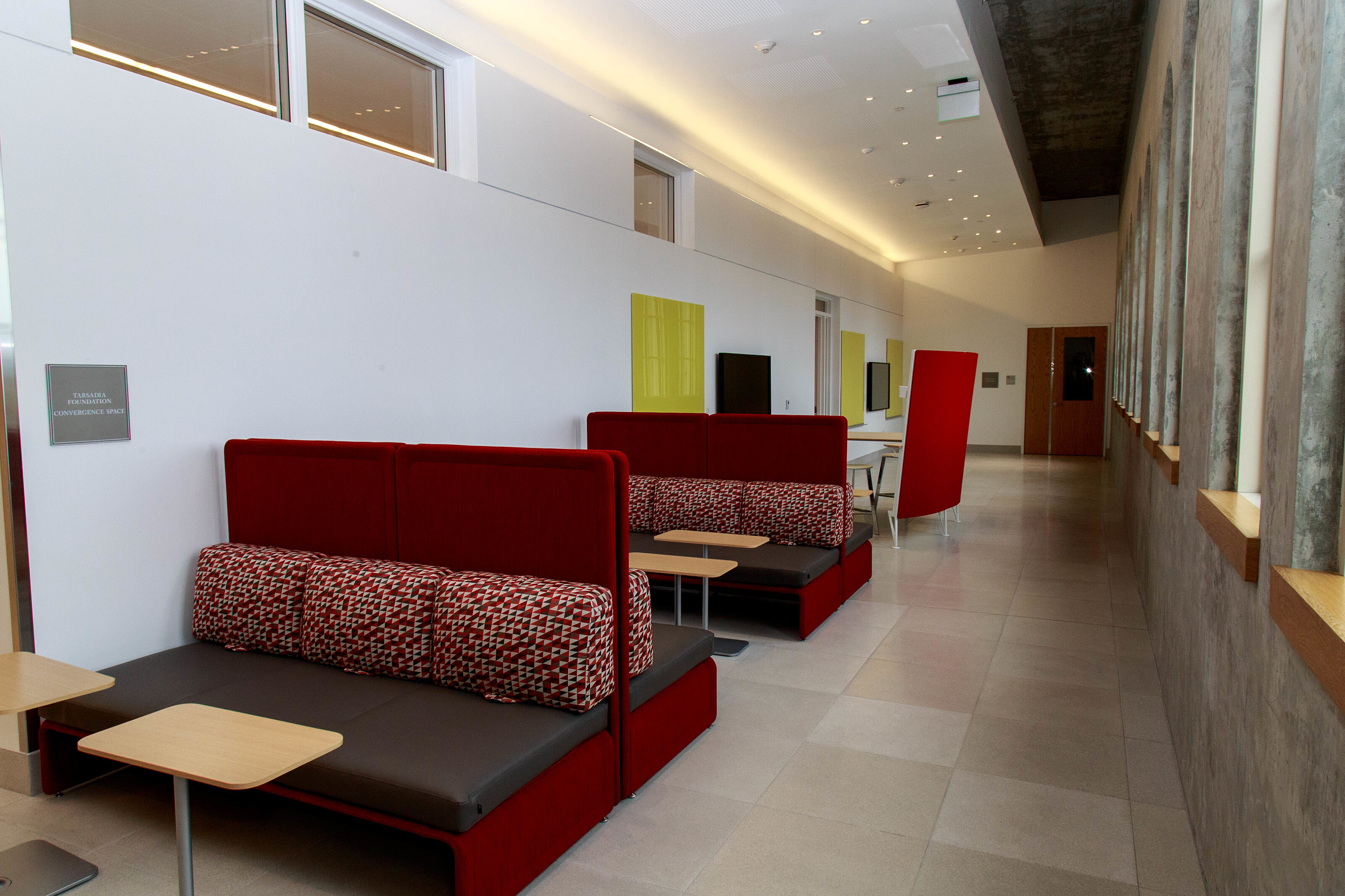 A small hallway with red booths and a desk on the side.