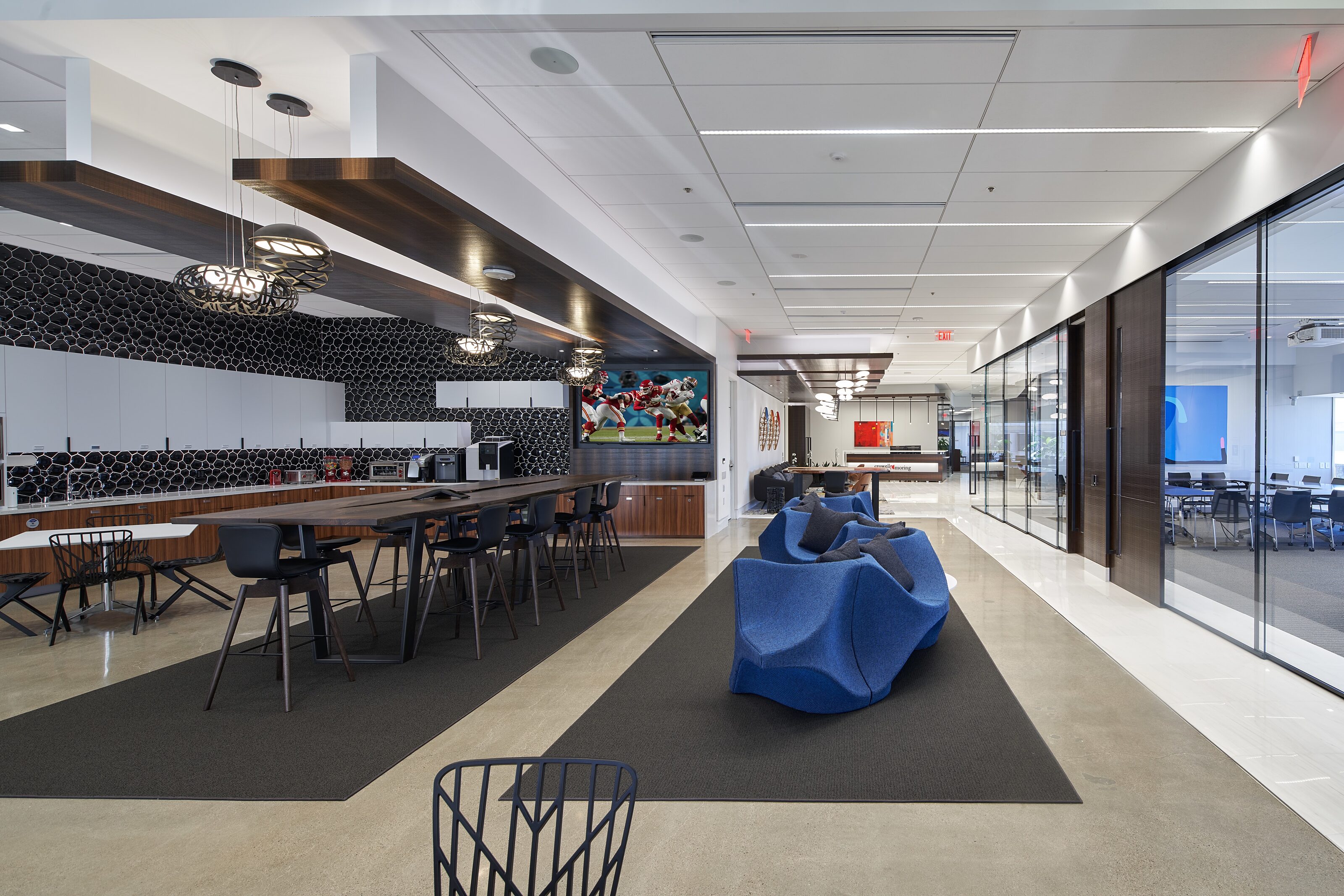 A chic breakout area with blue chairs and a wooden bar table.
