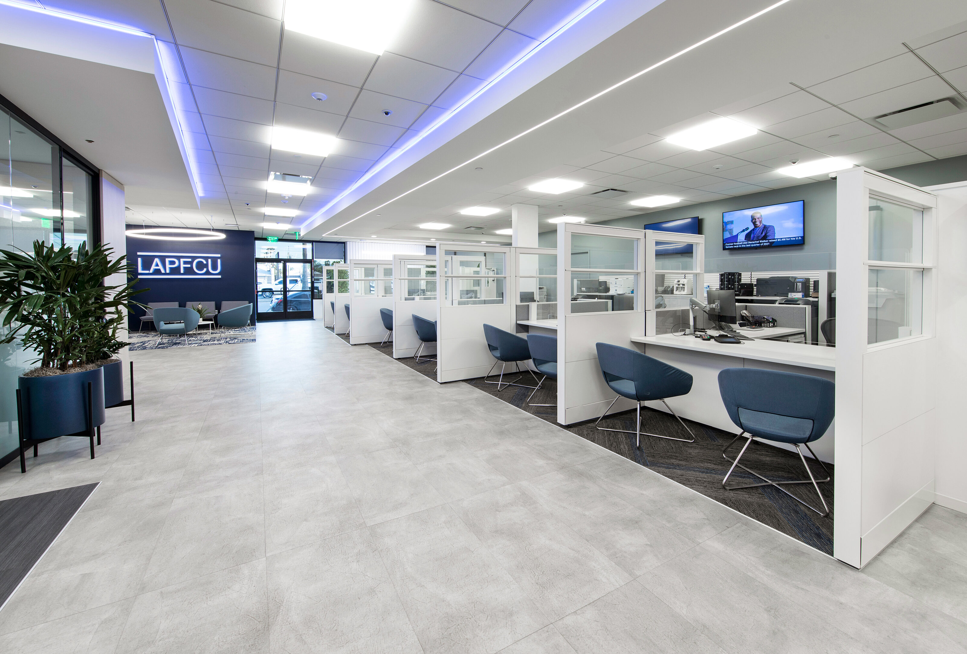 A number of blue lounge chairs are placed in front of the teller counters at the bank.