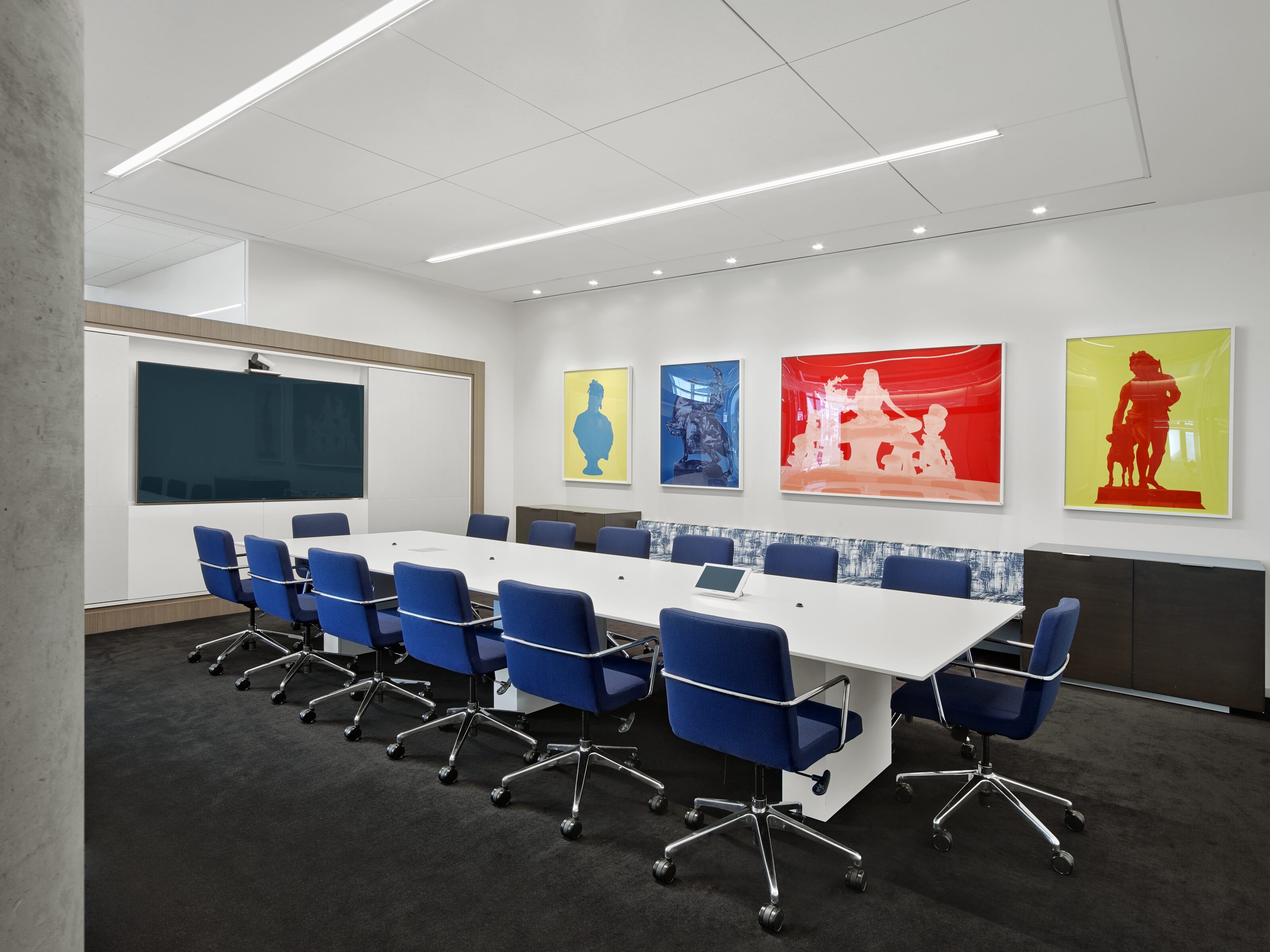 A conference room furnished with a sleek white meeting table and complemented by a few stylish blue office chairs.
