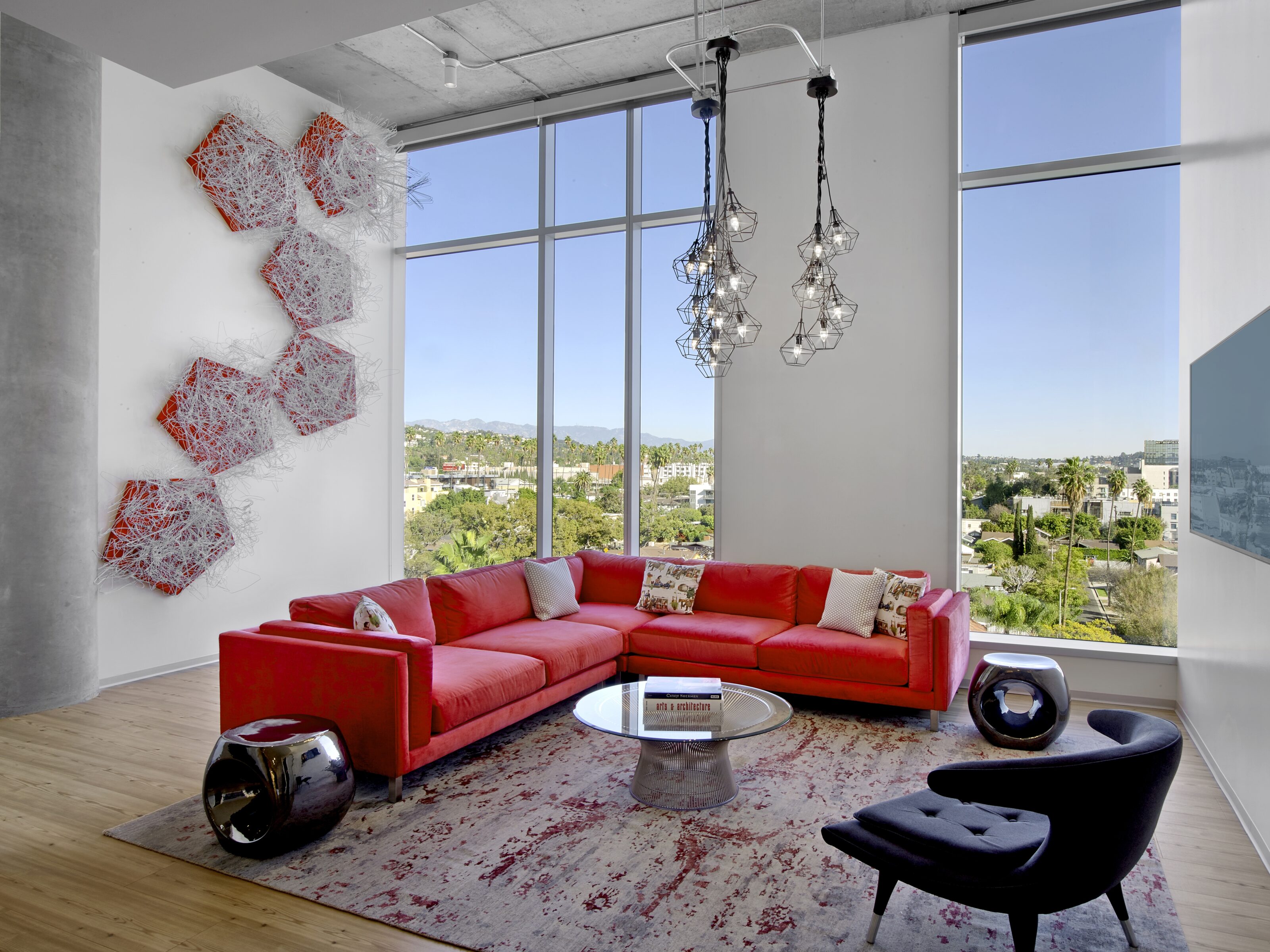 A open waiting area with red sofa and black lounge chairs with a glass made round coffee table.