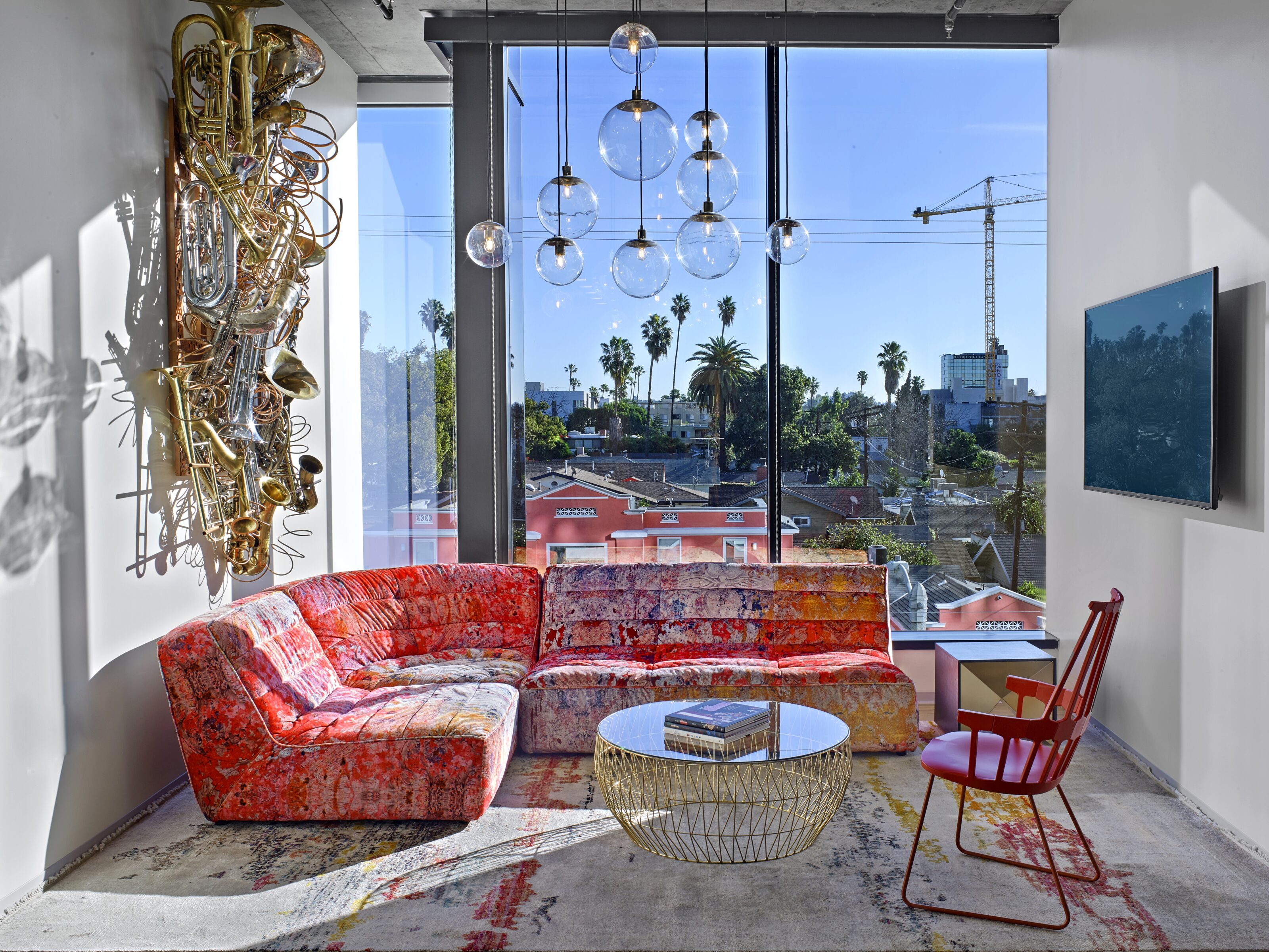 A stylish red sofa paired with a charming coffee table sits gracefully in front of a sunlit window, infusing the room with warmth and elegance.