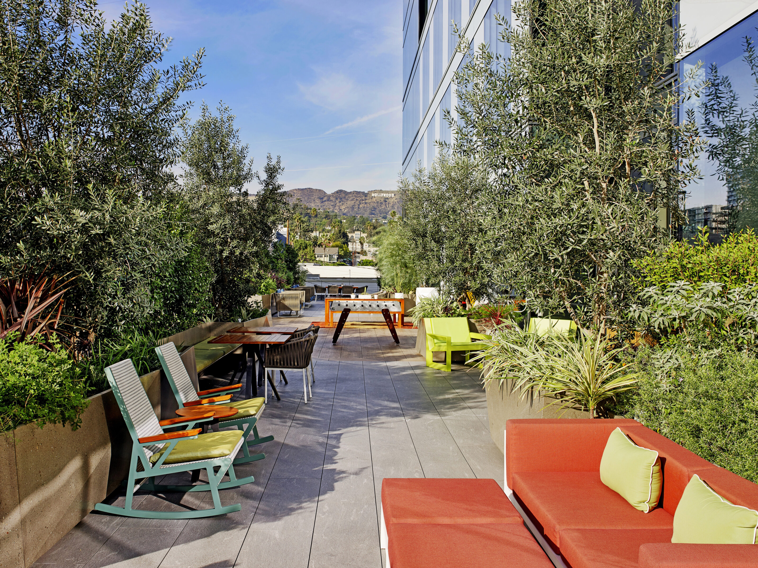 Red sofas and chairs are set among trees in an outdoor lounging area, creating a soothing atmosphere ideal for resting and unwinding.