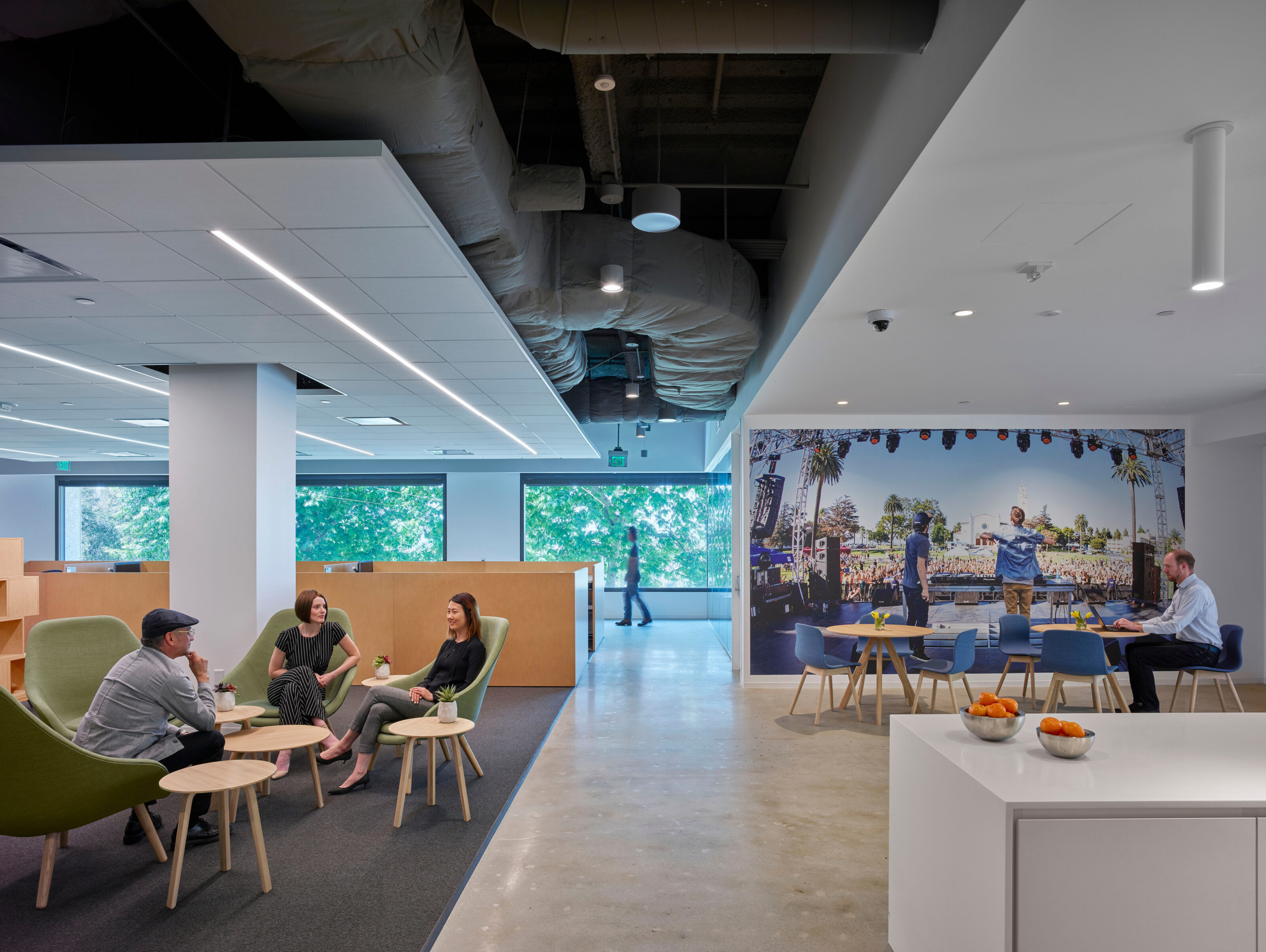 Green lounge chairs and a wooden occasional tables are set in an open area, while nearby, two cafe tables and chairs offer a place to rest and dine.