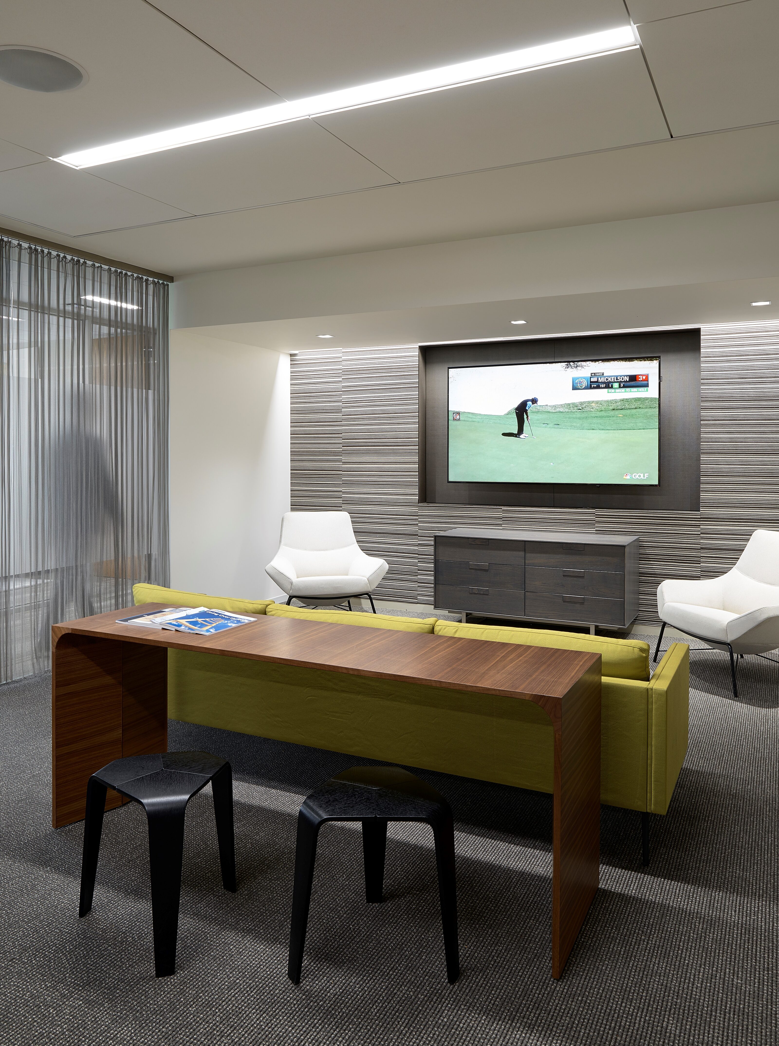 A relaxing breakout space with a bright yellow couch and comfy white lounge chairs.