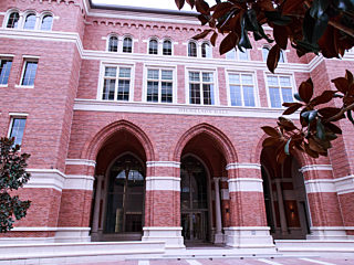 A grand red brick building exuding an air of sophistication and wealth, adorned with numerous French windows that infuse the interior with natural light.