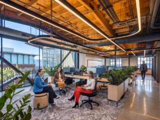 Three ladies collaborating in an office with workstations.