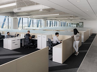 Individual workstations are set up with wooden walls in a room with French windows that look out on a beautiful view of the city.