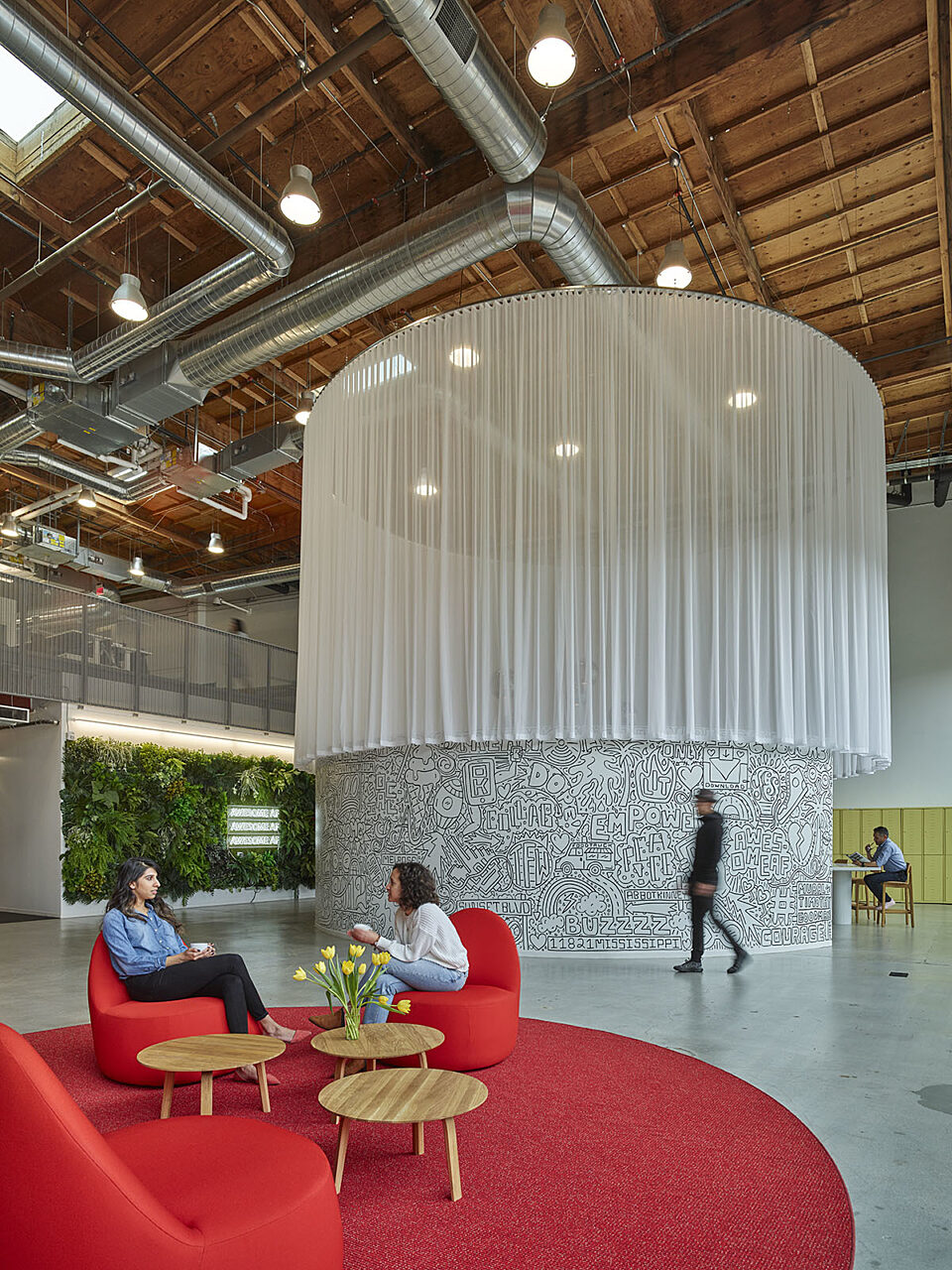 A lively breakout area with a red carpet and comfy lounge chairs for relaxation and refreshment.