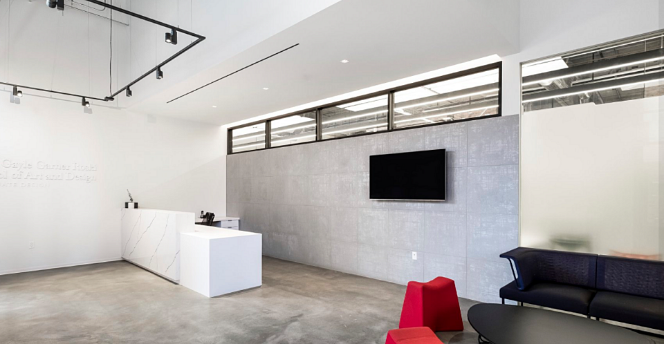 This welcome space has a white marble reception desk, black lounge chairs, and a coffee table. The ottomans by the coffee table add red.