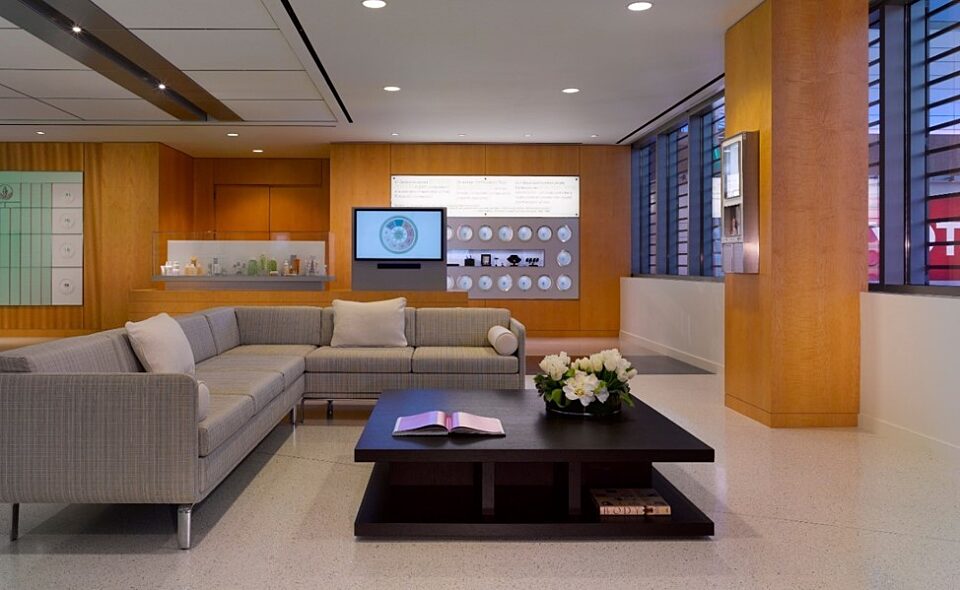 A room with a coffee table and grey sofas. Warm wooden walls make the area inviting.