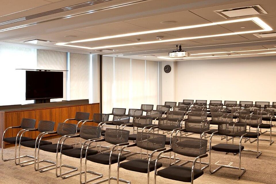 Assembly room with folding chairs and a side television for presentations or media.