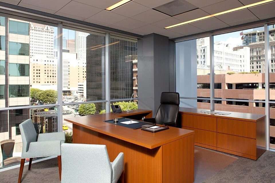 A private office space with a wooden desk, complemented by two white lounge chairs and a black office chair for a stylish and comfortable work environment