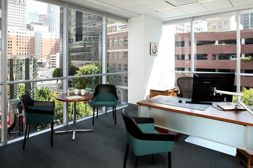 A private office with an executive desk, seats, and beautiful plants.