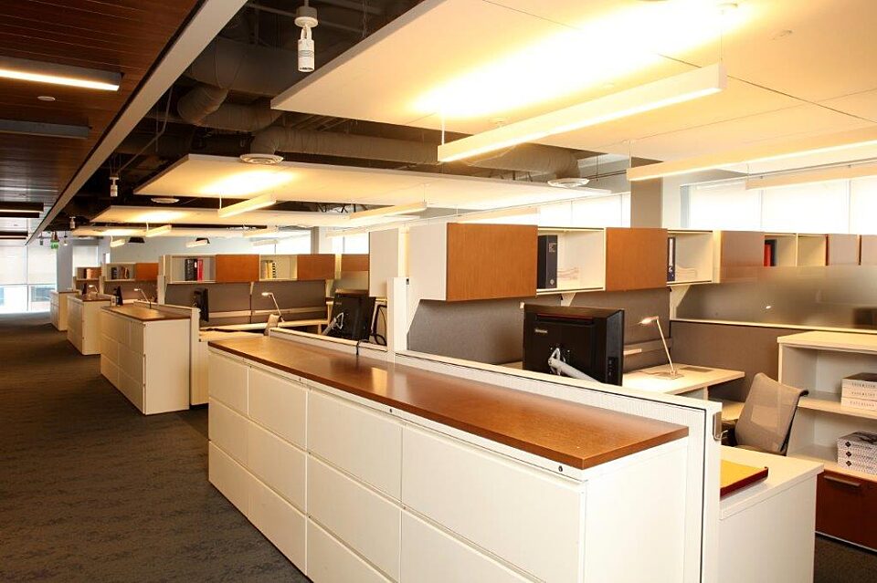 An efficient open office with close workstations. Each workstation has a computer, storage, desk, and chair for productivity and collaboration.
