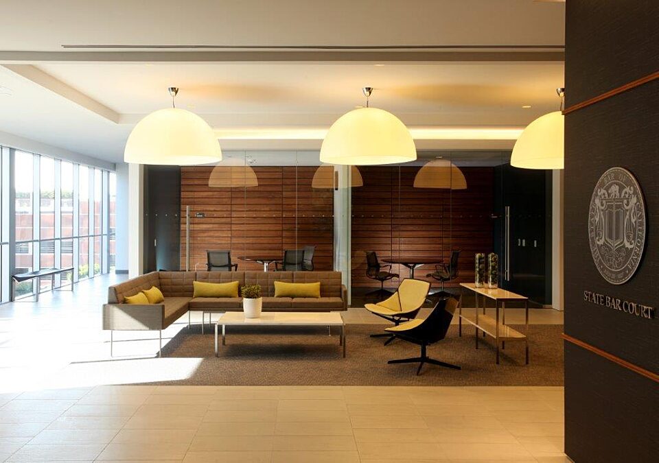 A spectacular living area with an L-shaped sofa, two lounge chairs, and two separate offices with glass walls.