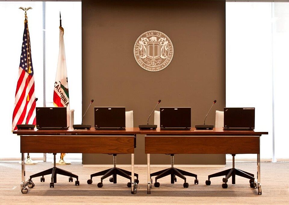3 conference tables and 4 office chairs arranged in front of the flag.