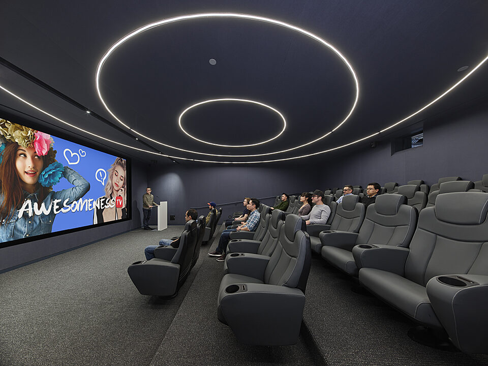 A screen room with row of black leather chair..
